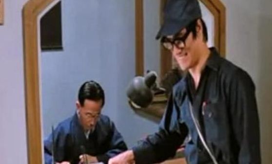 Bruce Lee ne reaminteste ca are talente   actoricesti ascunse diferite fata de cele de   luptator atunci cand este fortat sa se   deghizeze intr-un inginer imbracat in salopeta   si cu ochelari mari pe ochi